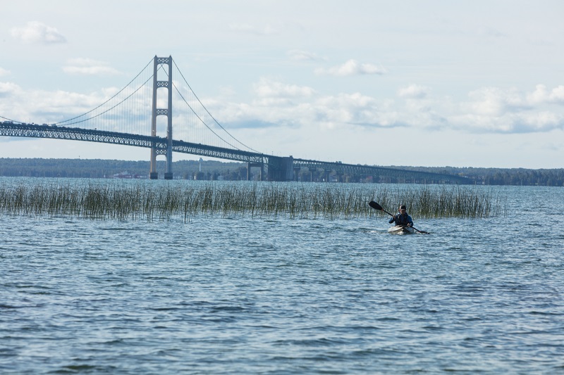 Man kayaking with bridge in background